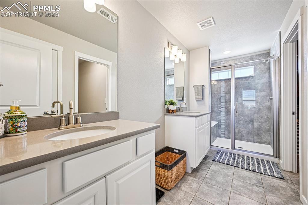 Image 28 of 50: En suite primary bathroom with walk in closet, custom stand in shower and d