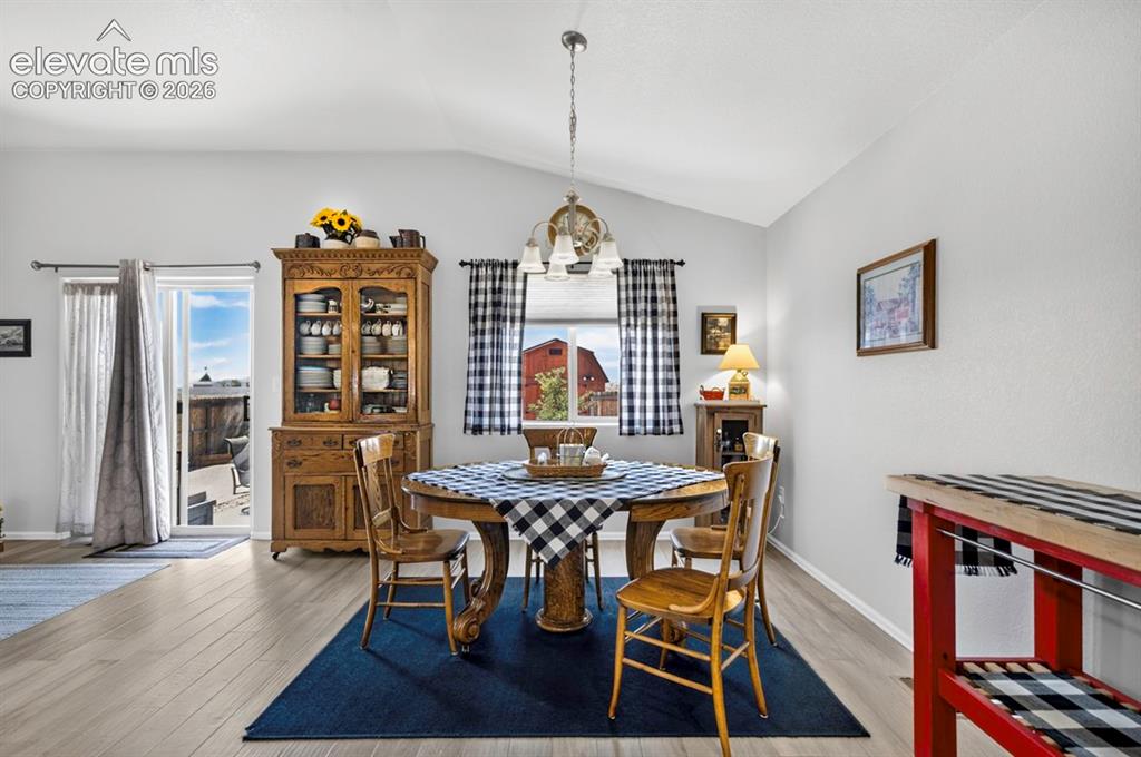 Image 10 of 40: Vaulted ceilings enhance this dining area featuring wood-finish flooring, a