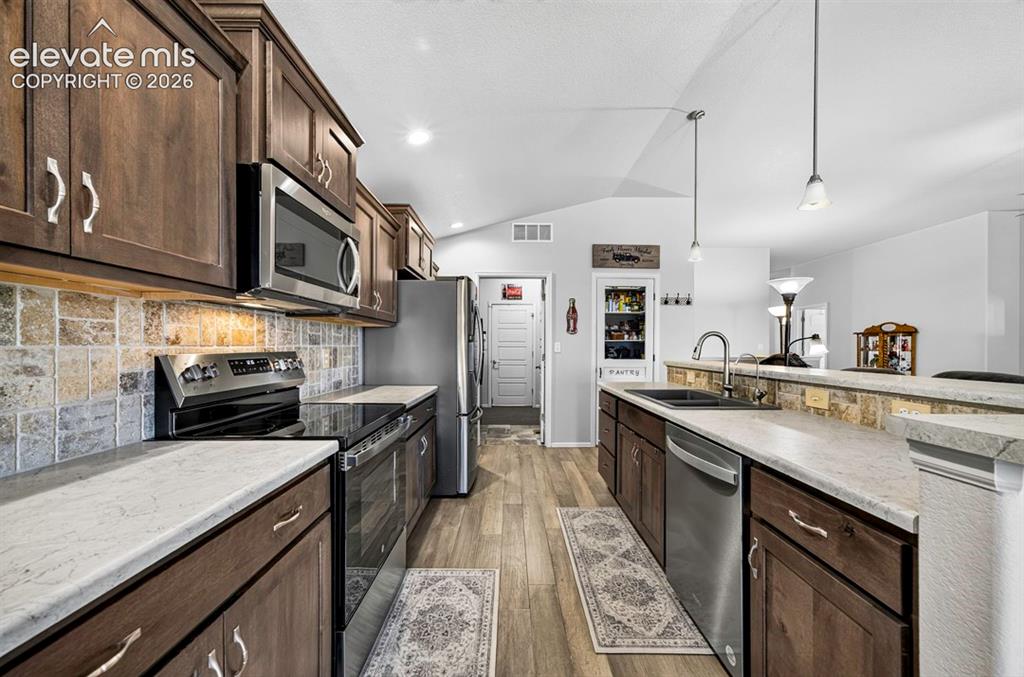 Image 13 of 40: Kitchen featuring wood-finish cabinetry, stainless steel appliances, stone-