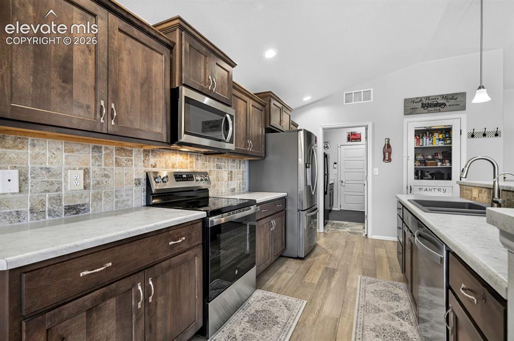 Image 15 of 40: Kitchen featuring wood-finish cabinetry, light-toned countertops, stainless