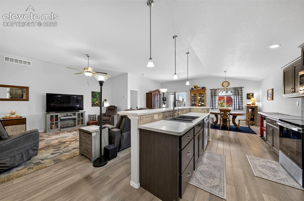 Image 16 of 40: Open-concept living space featuring wood-finish flooring, vaulted ceilings,