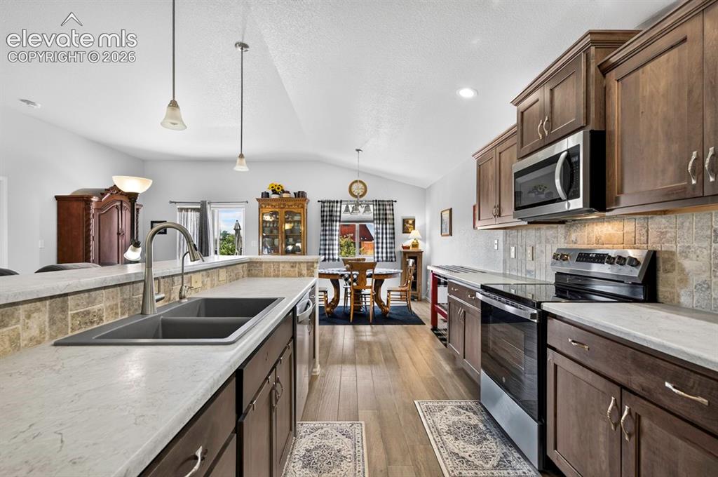 Image 18 of 40: Open-concept kitchen featuring wood-finish flooring, dark wood cabinetry, a