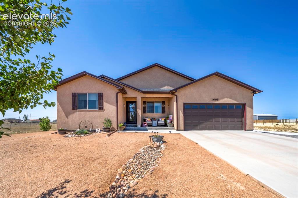 Image 2 of 40: Stucco exterior with a covered entry, attached garage, and concrete drivewa