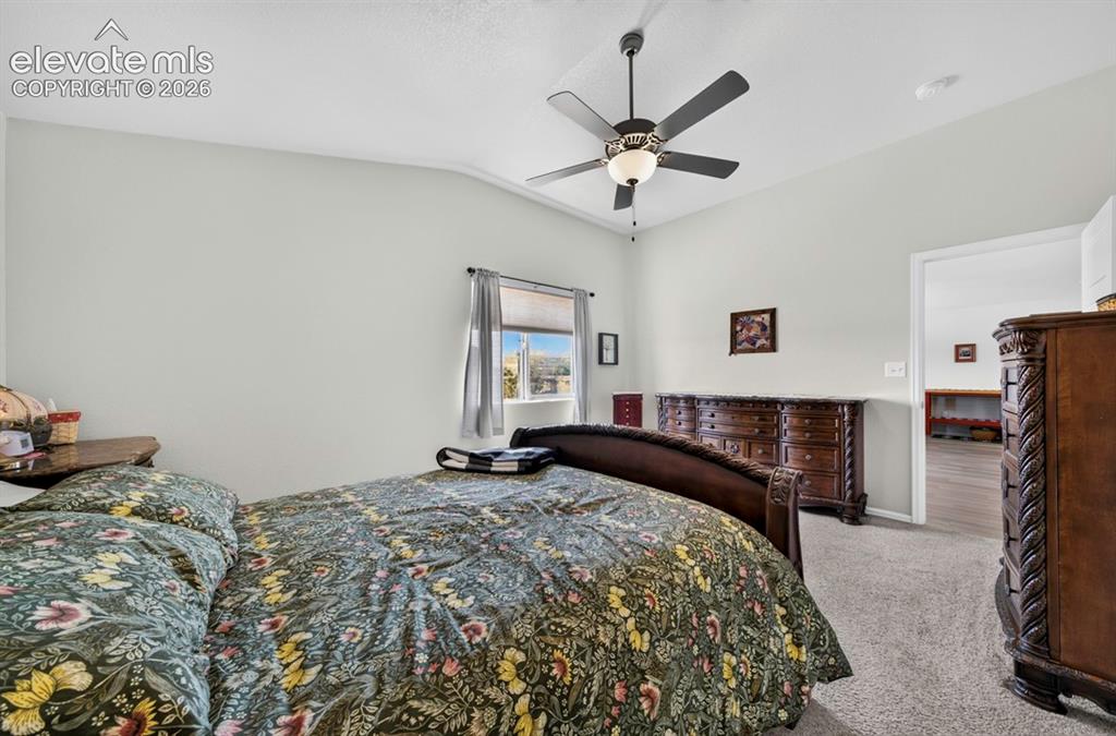 Image 21 of 40: MB Carpeted bedroom featuring vaulted ceilings, a ceiling fan with integrat