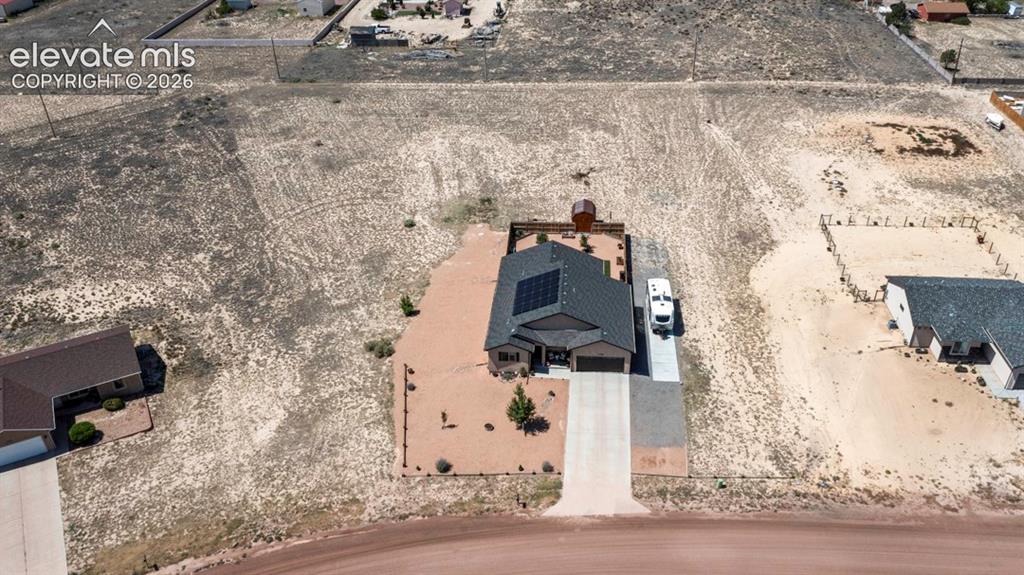 Image 3 of 40: Modern ranch-style home featuring a dark shingle roof with solar panels, an