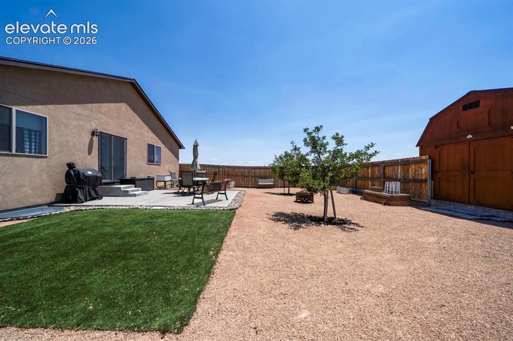 Image 36 of 40: Expansive backyard featuring a stucco exterior, a concrete patio, a privacy