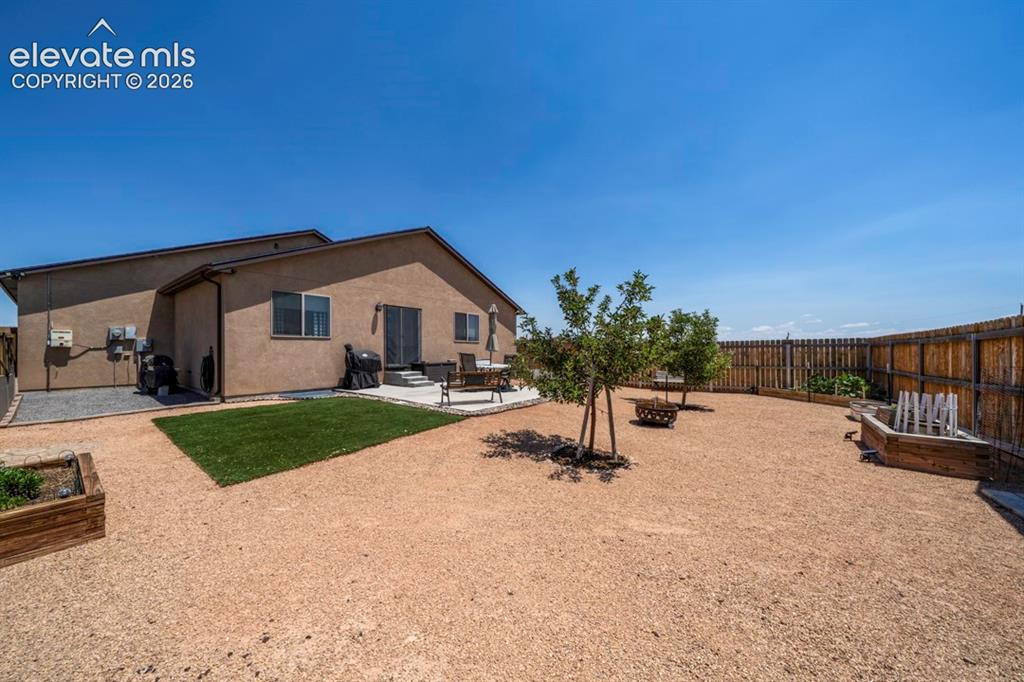 Image 39 of 40: Expansive backyard featuring a gravel landscape, a concrete patio, and a pr