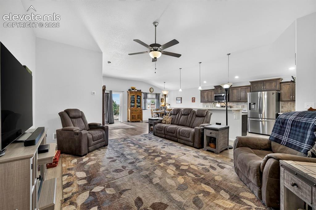 Image 5 of 40: Spacious open-concept living area featuring wood-finish flooring, vaulted c