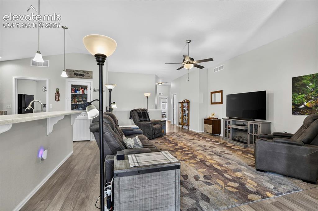 Image 6 of 40: Vaulted ceilings enhance the main living area, featuring wood-finish floori