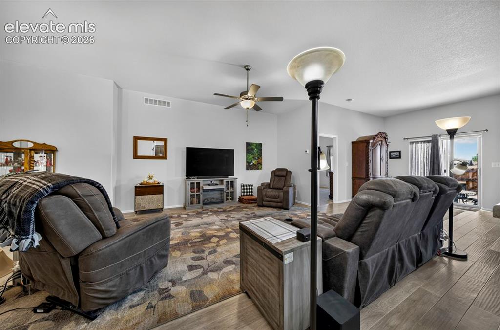 Image 7 of 40: Spacious living area featuring wood-finish flooring and a central ceiling f