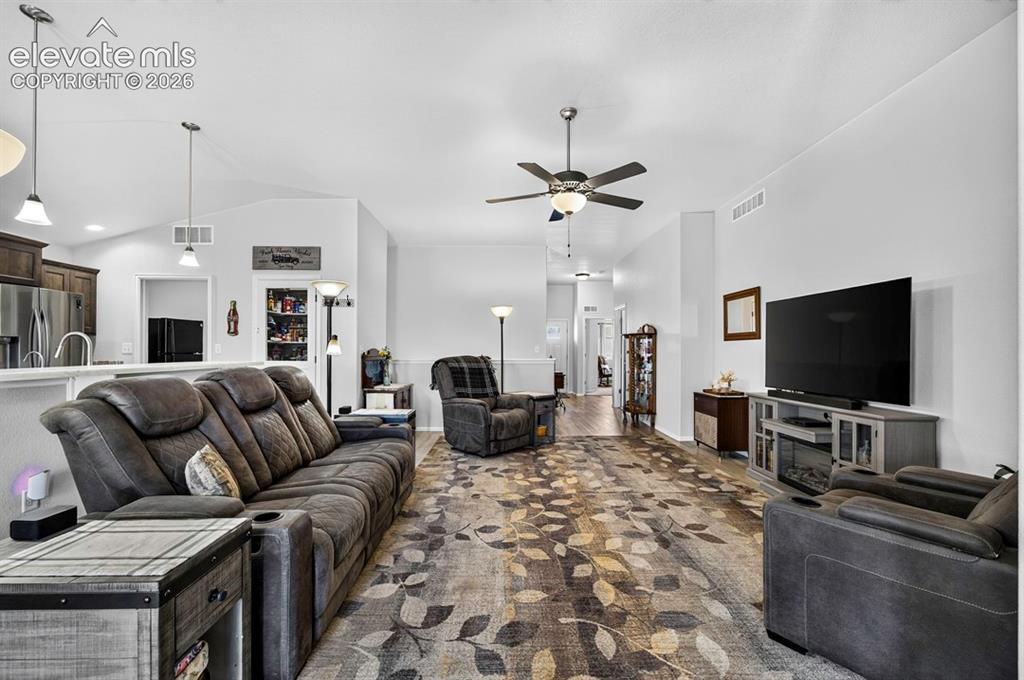 Image 8 of 40: Open-concept living space featuring vaulted ceilings, a ceiling fan with in