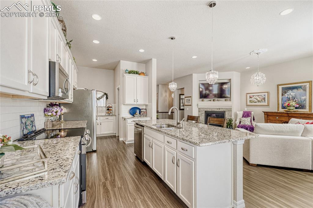 Image 10 of 30: Kitchen featuring stainless steel appliances, open floor plan, white cabine
