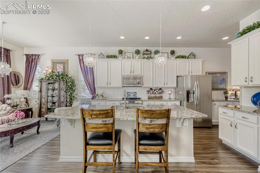Image 12 of 30: Kitchen with hanging lights, stainless steel appliances, a kitchen island w