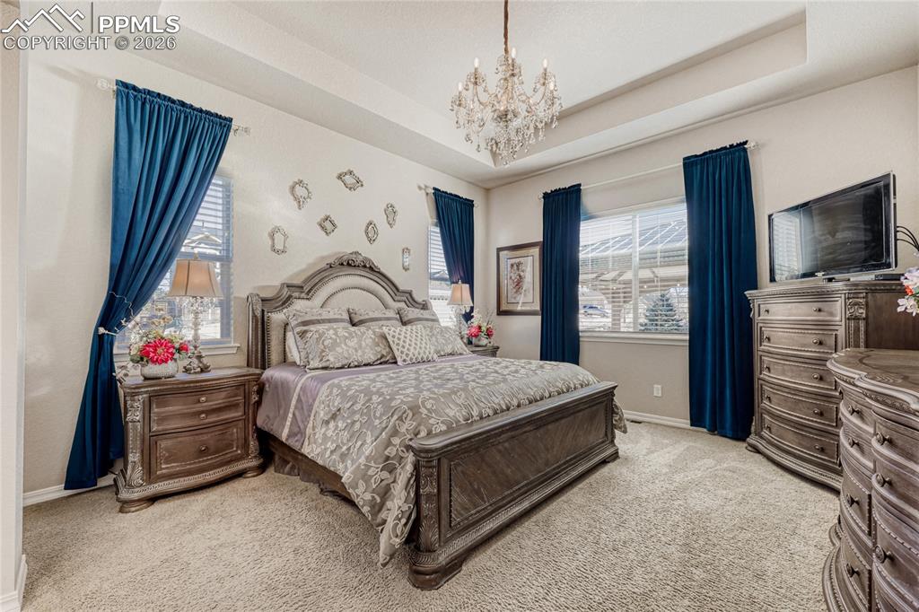 Image 17 of 30: Master Bedroom with  tray ceiling, chandelier and light carpet