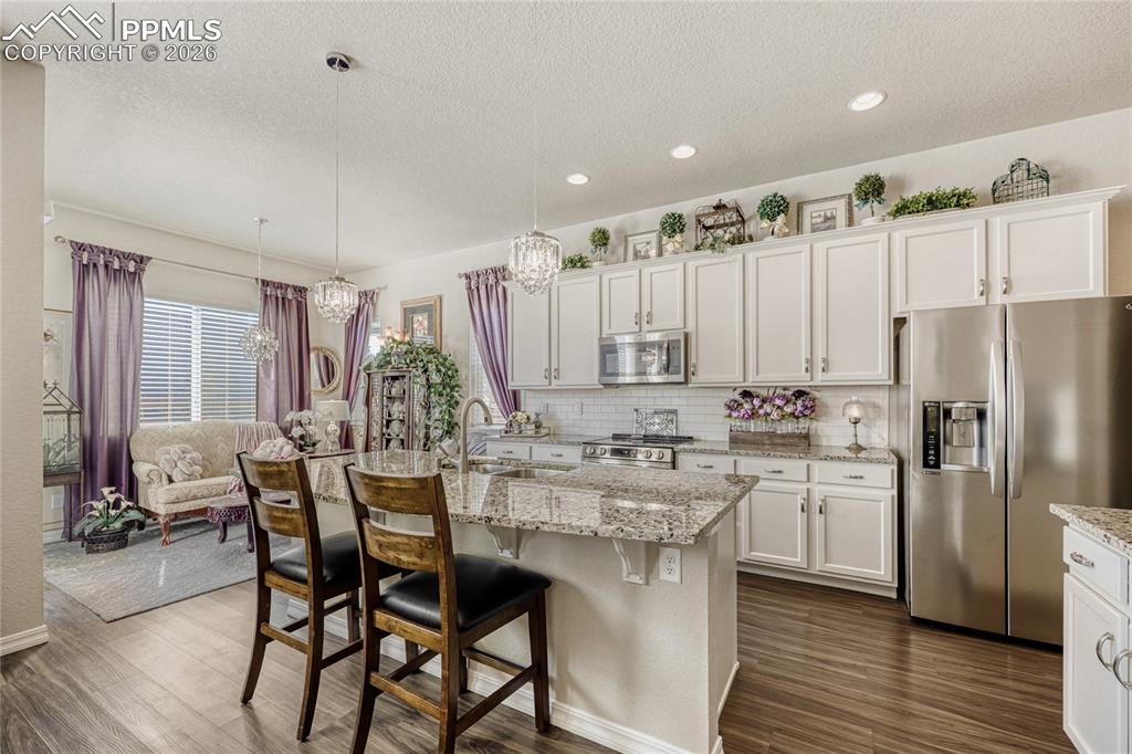 Image 8 of 30: Kitchen featuring stainless steel appliances, white cabinetry, a breakfast 