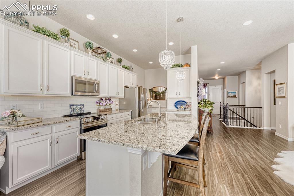 Image 9 of 30: Kitchen with white cabinetry, stainless steel appliances, a breakfast bar, 
