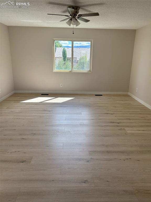 Image 5 of 6: Empty room featuring light wood-style floors, a textured ceiling, and ceili