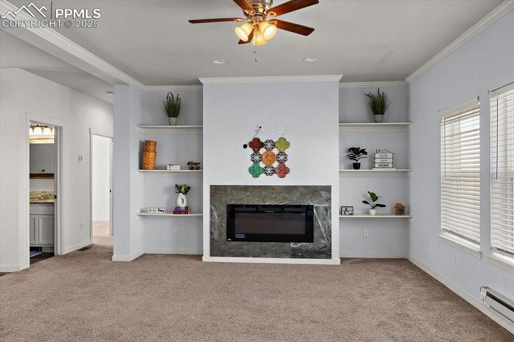 Image 10 of 33: Unfurnished living room with built in shelves, crown molding, a premium fir