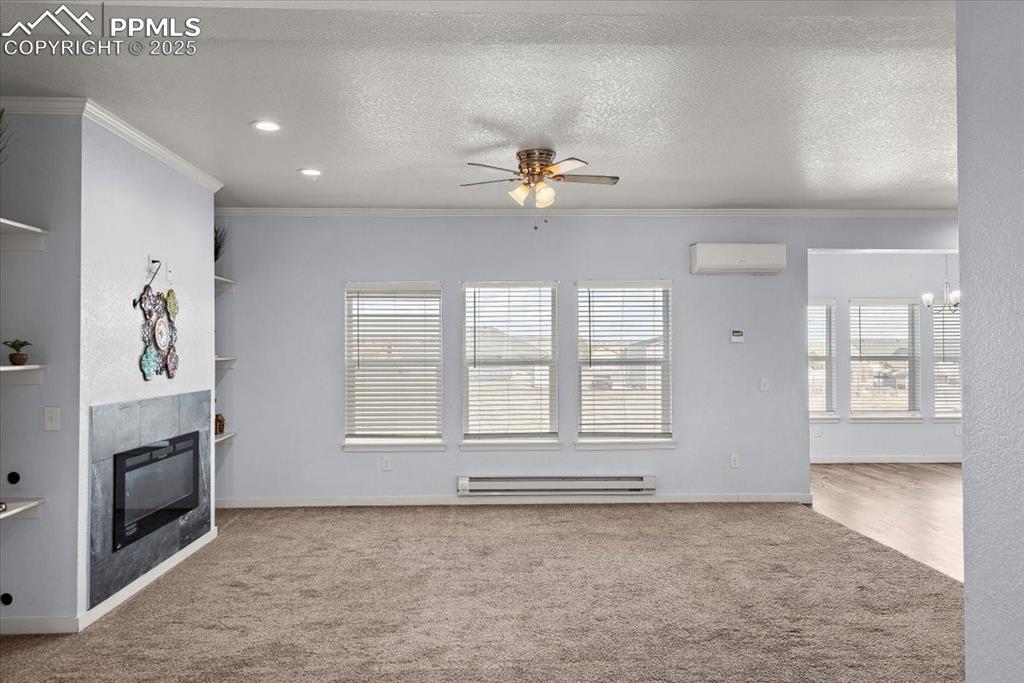 Image 11 of 33: Unfurnished living room with ornamental molding, baseboard heating, a textu