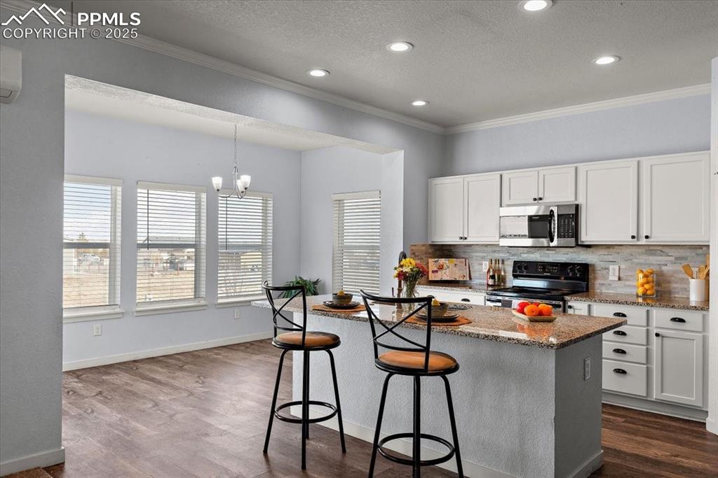 Image 14 of 33: Kitchen with decorative backsplash, stainless steel microwave, light stone