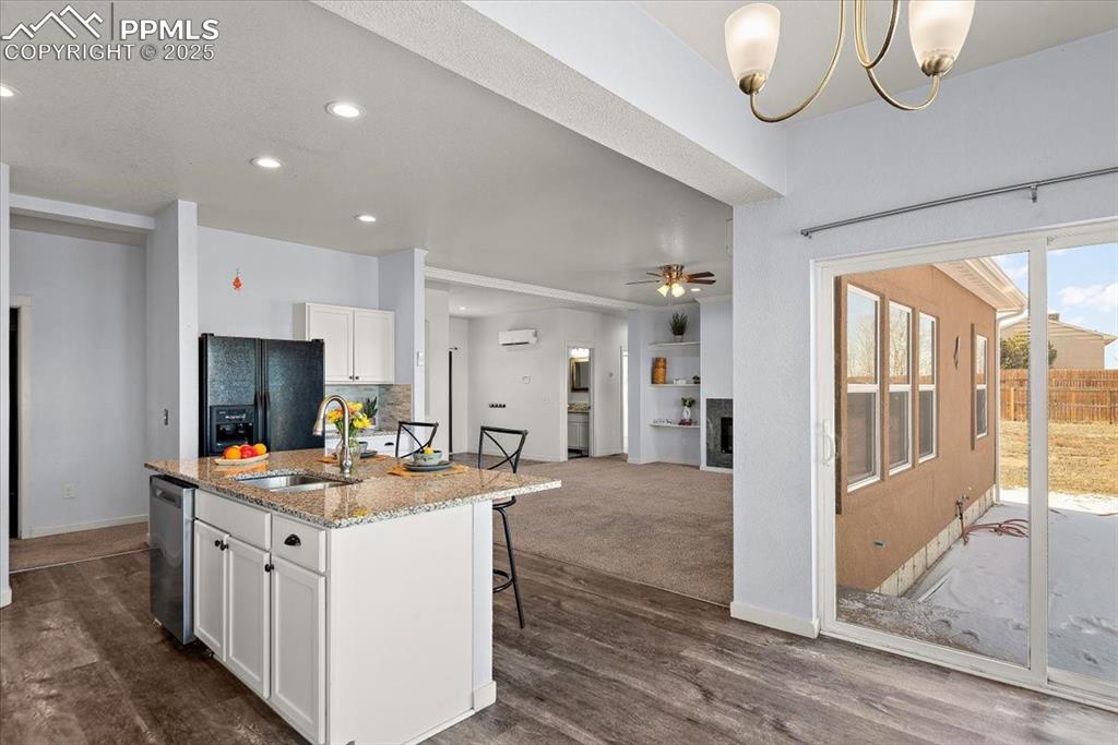Image 15 of 33: Kitchen featuring light stone counters, white cabinetry, dishwasher, and an
