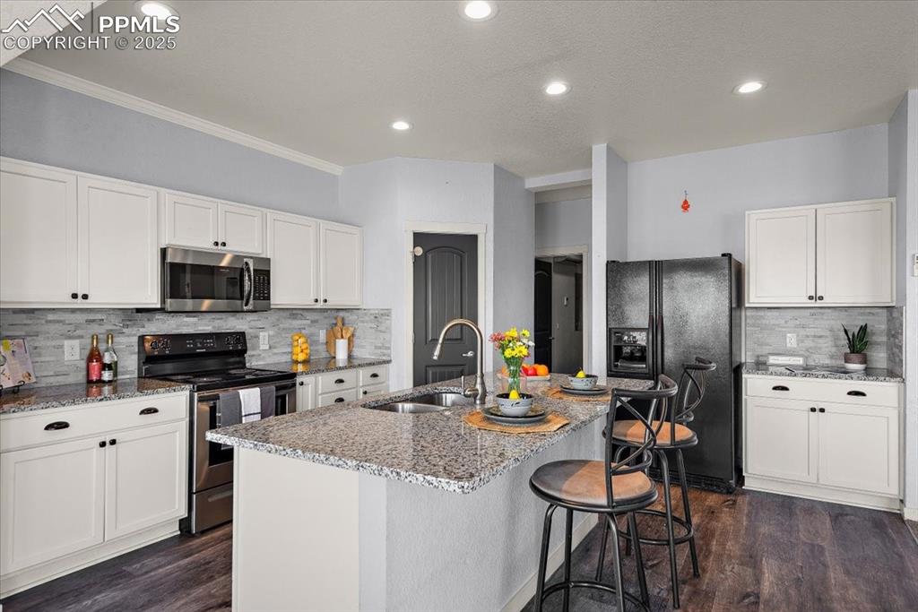 Image 16 of 33: Kitchen with stainless steel appliances, white cabinetry, a center island w