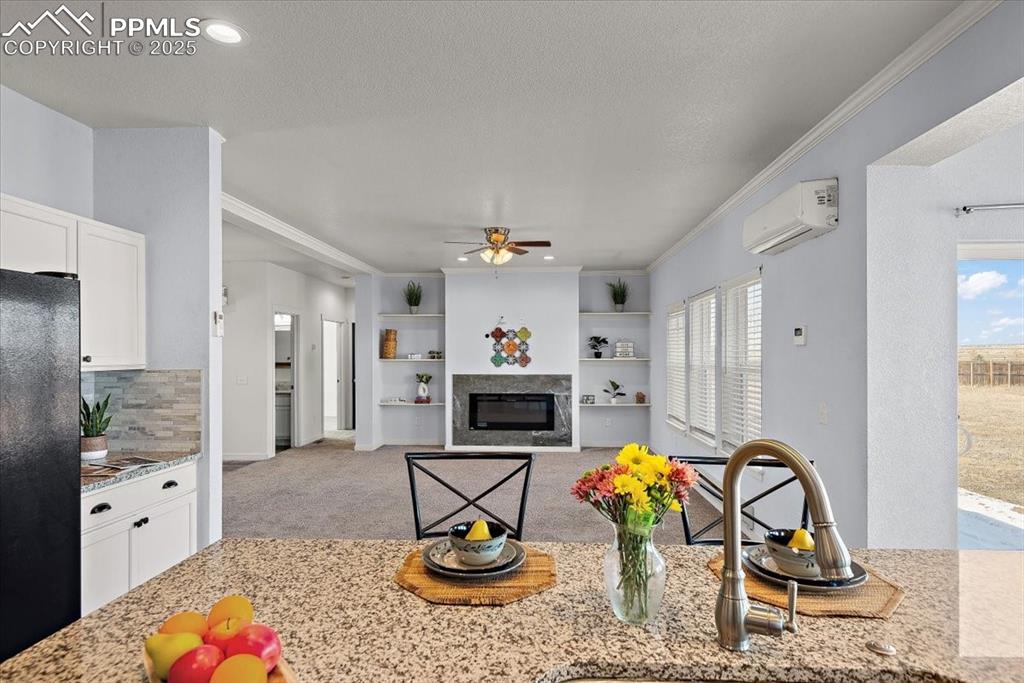 Image 18 of 33: Kitchen featuring light carpet, white cabinets, a glass covered fireplace,