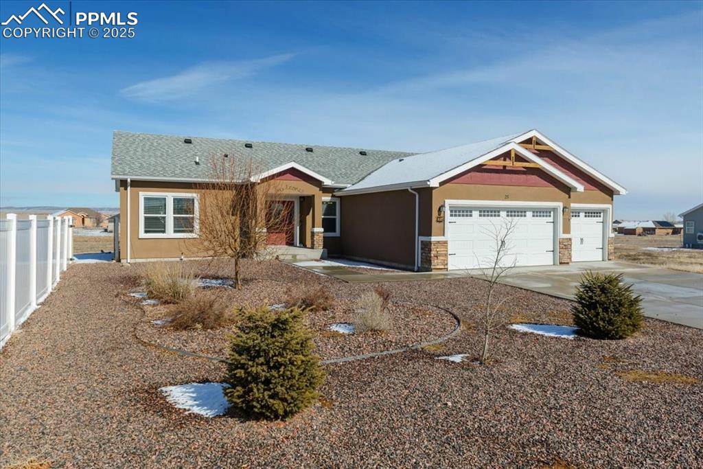 Image 2 of 33: View of front facade with stucco siding, fence, a garage, stone siding, and