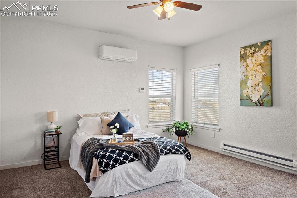 Image 24 of 33: Carpeted bedroom with a wall unit AC, a baseboard radiator, a textured wall