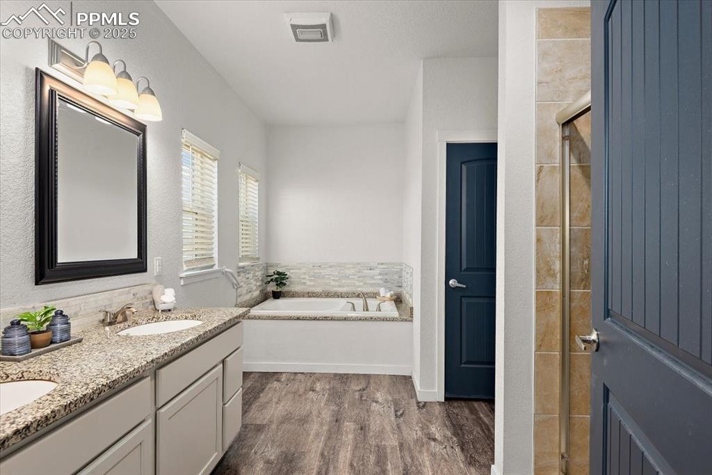 Image 25 of 33: Bathroom featuring double vanity, visible vents, wood finished floors, a ga