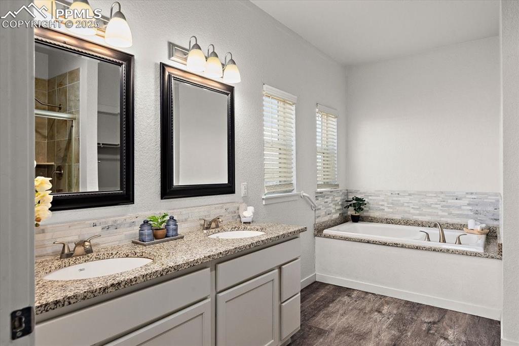 Image 26 of 33: Bathroom featuring double vanity, a garden tub, a sink, and wood finished f