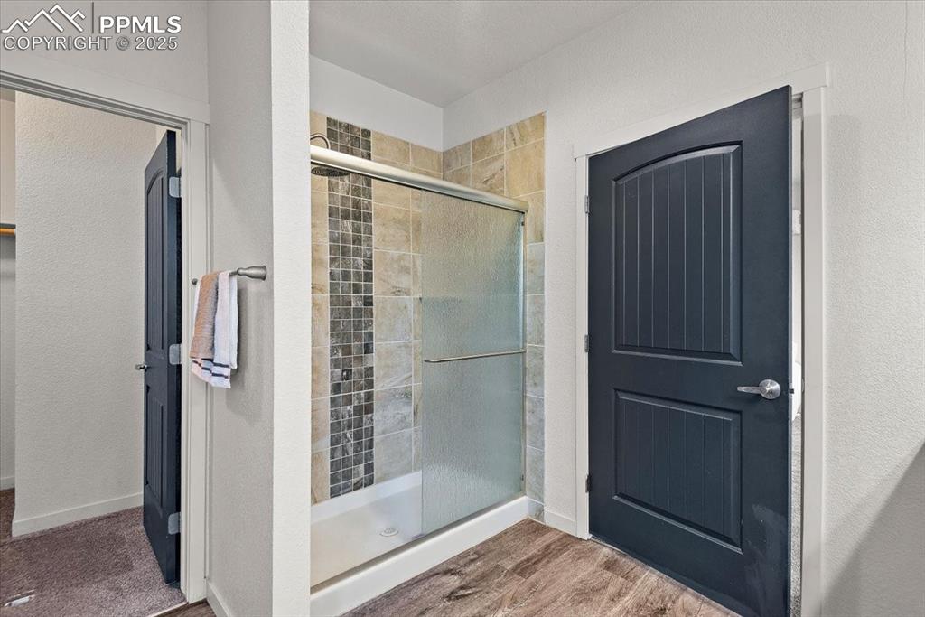 Image 27 of 33: Full bath featuring a shower stall, baseboards, and wood finished floors