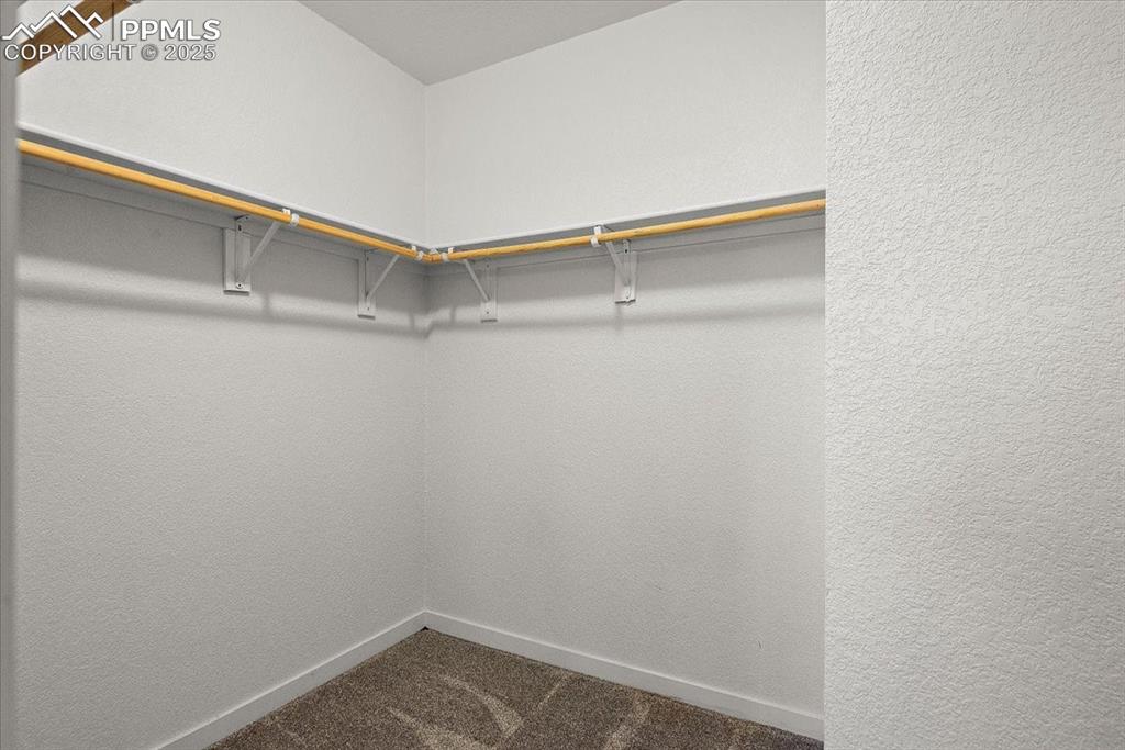 Image 28 of 33: Walk in closet featuring dark colored carpet