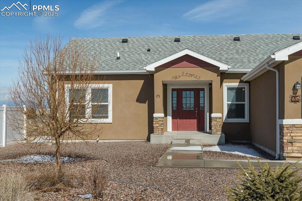 Image 3 of 33: View of exterior entry featuring stone siding, a shingled roof, and stucco