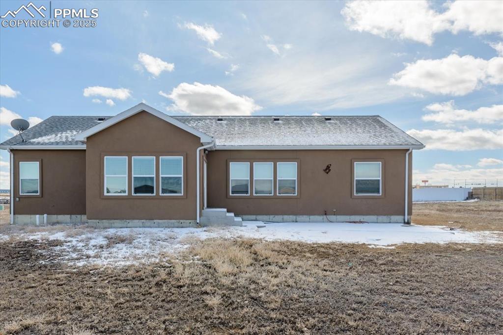 Image 31 of 33: Back of house featuring stucco siding and roof with shingles