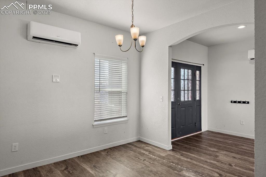 Image 5 of 33: Entrance foyer with dark wood-style floors, arched walkways, a wall unit a