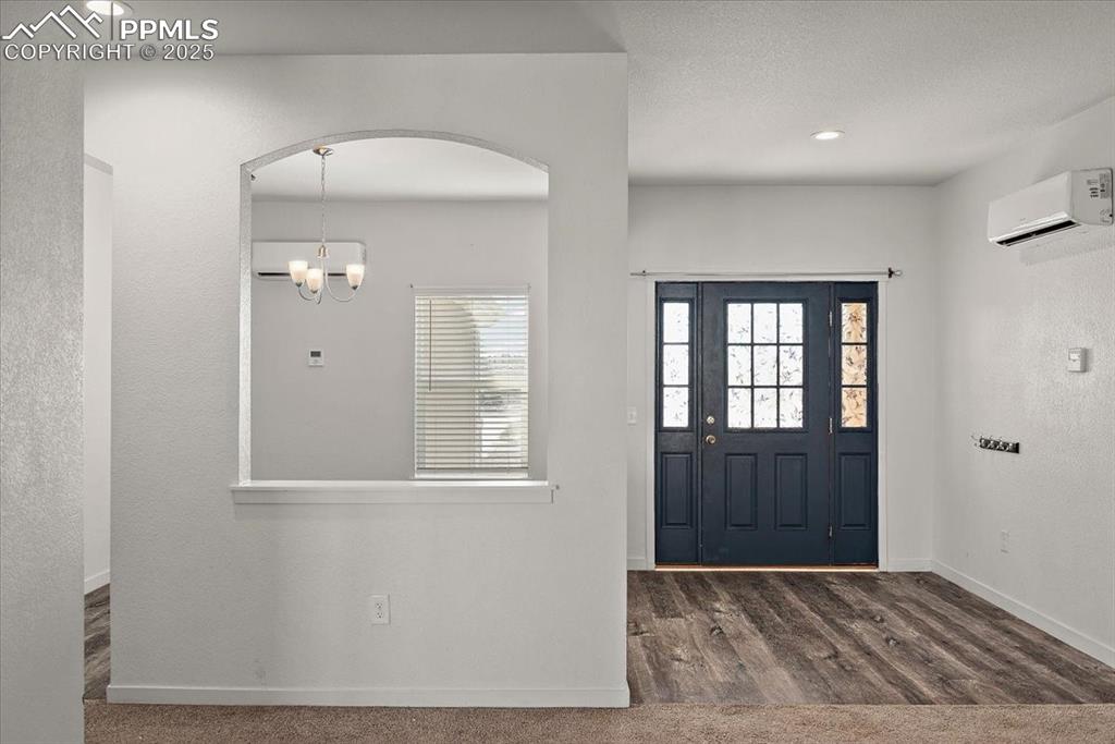 Image 7 of 33: Entryway with arched walkways, a wall unit AC, a notable chandelier, and ba