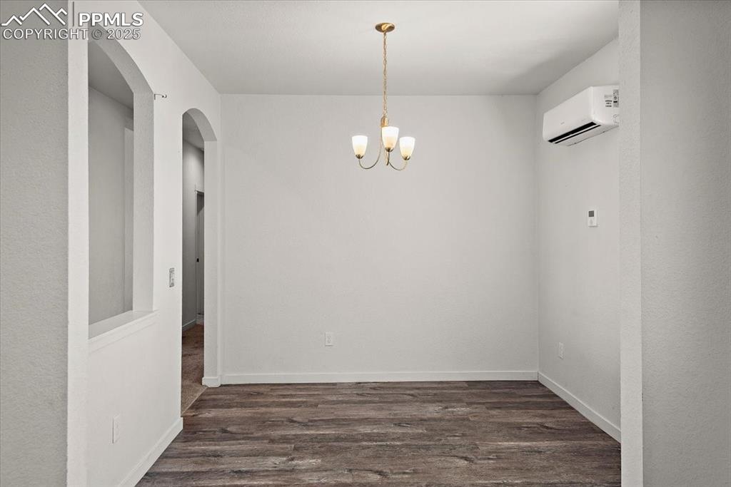 Image 8 of 33: Empty room with dark wood-style flooring, a wall mounted AC, an inviting ch