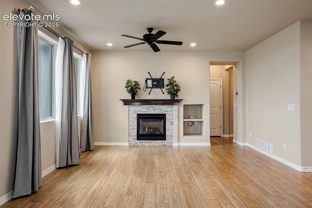 Image 11 of 48: Living room with gas fireplace and ceiling fan