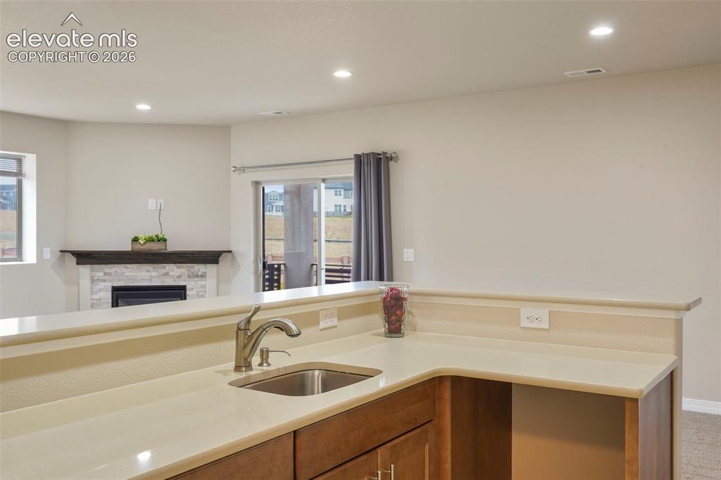 Image 22 of 48: Wet bar area with upgraded quartz countertop, tile floor and storage area