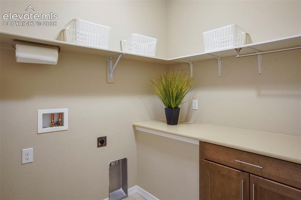 Image 31 of 48: Main Level Laundry with tile floor, storage cabinet and shelves