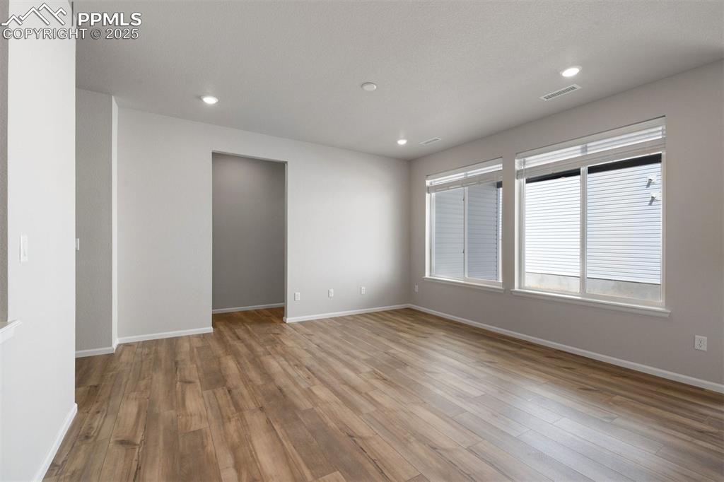 Image 16 of 33: Empty room with light wood finished floors and recessed lighting