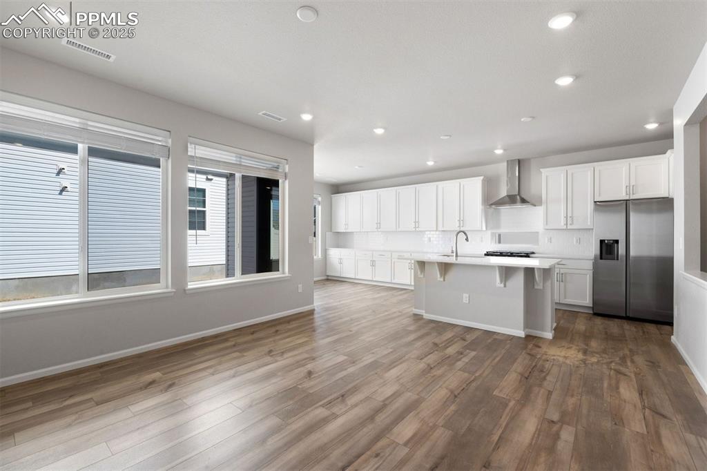 Image 17 of 33: Kitchen with white cabinets, stainless steel fridge with ice dispenser, a b