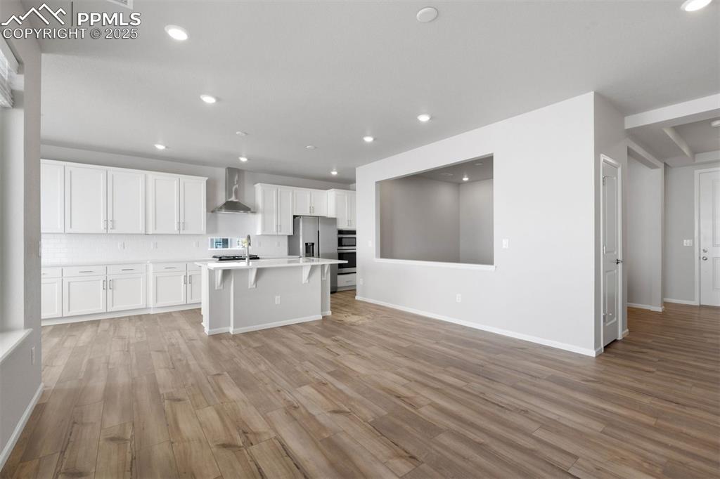 Image 18 of 33: Kitchen featuring white cabinets, a breakfast bar area, light wood finished