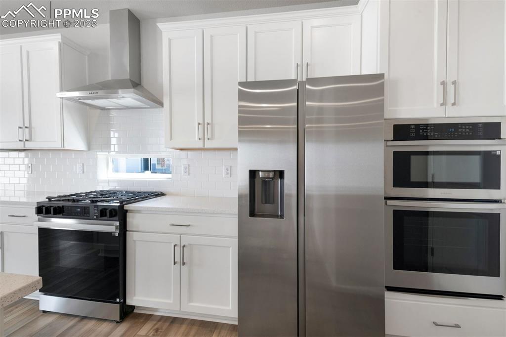 Image 19 of 33: Kitchen featuring stainless steel appliances, wall chimney range hood, whit