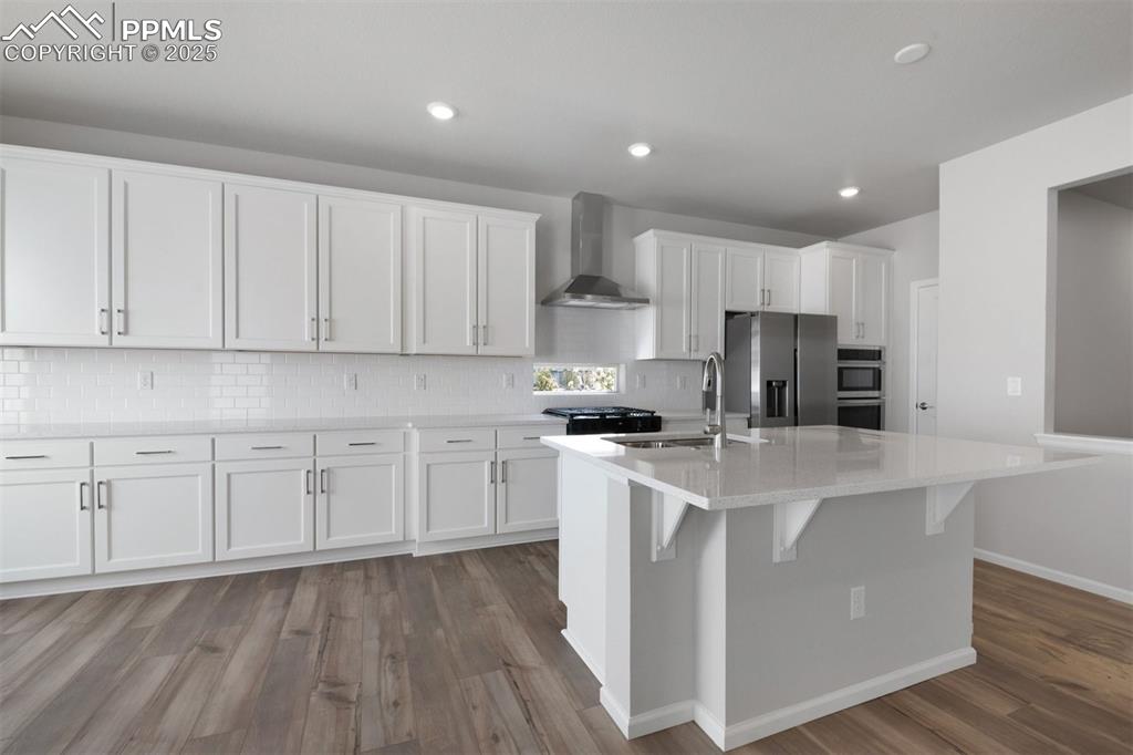 Image 21 of 33: Kitchen with white cabinets, appliances with stainless steel finishes, wall