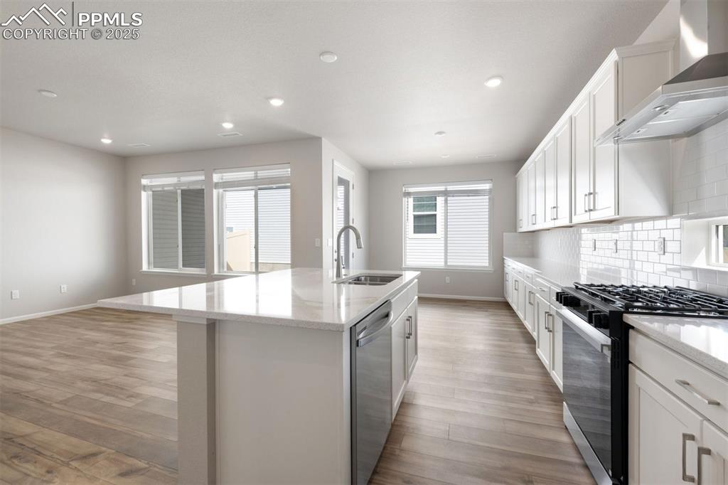 Image 23 of 33: Kitchen featuring black range with gas stovetop, wall chimney exhaust hood,