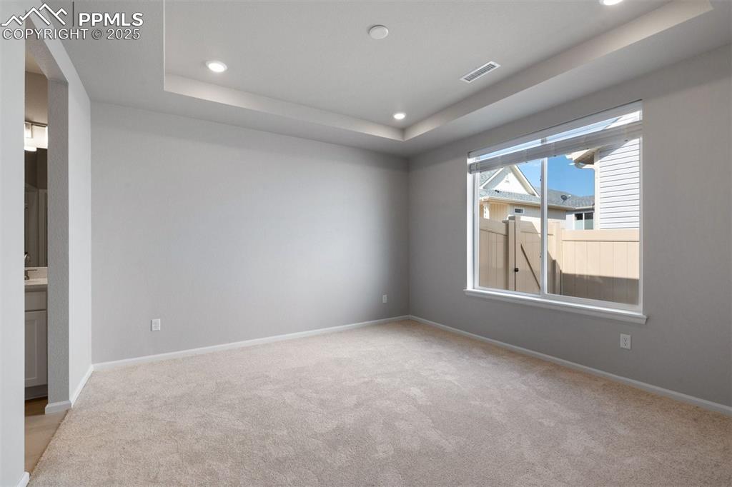 Image 27 of 33: Empty room featuring a raised ceiling, light carpet, and recessed lighting