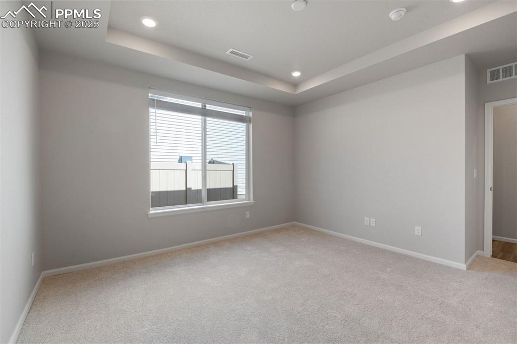 Image 28 of 33: Empty room featuring a raised ceiling, recessed lighting, and light colored