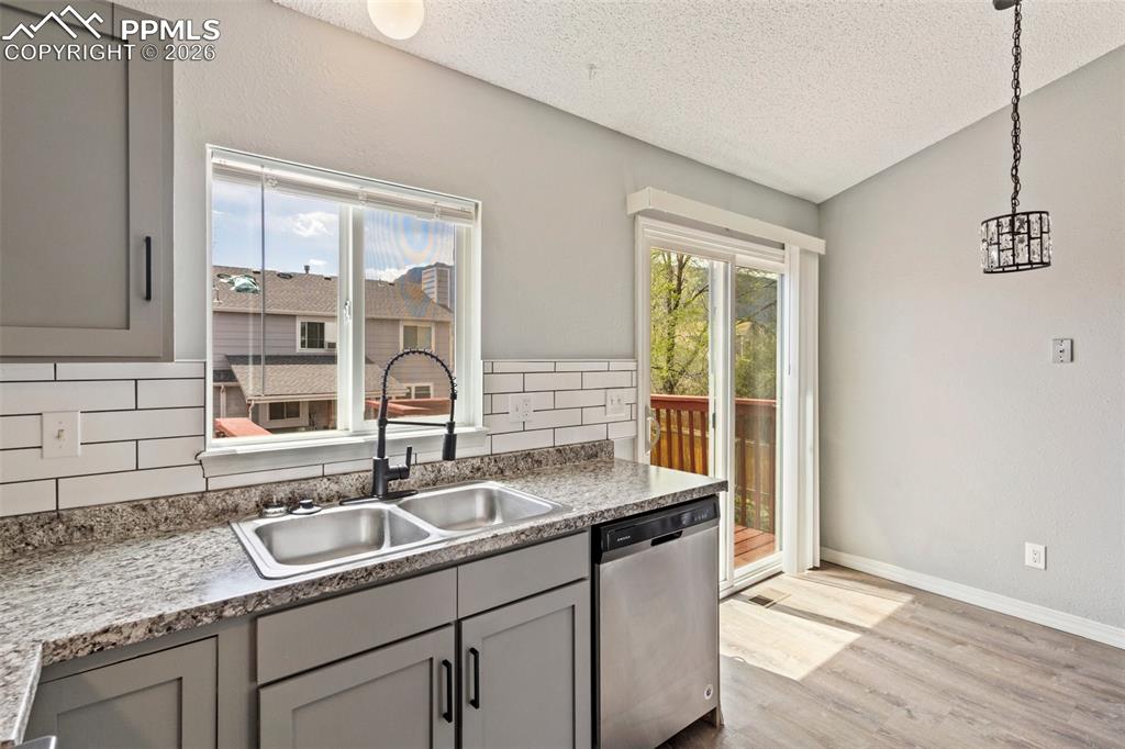 Image 11 of 35: Kitchen featuring gray cabinets, dishwasher, healthy amount of natural ligh